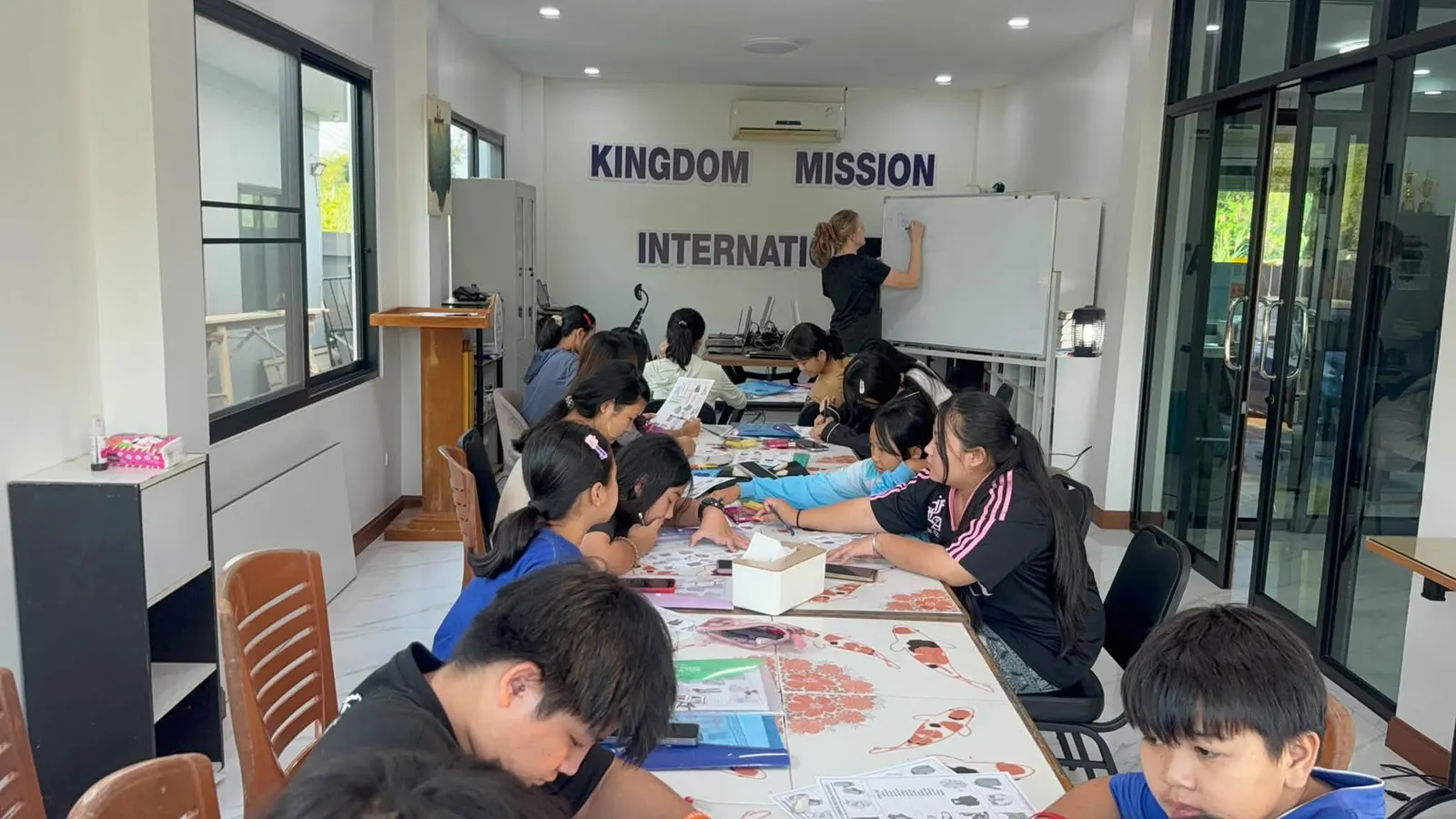 Students at work around tables in the KMI-Foundation Thailand classroom