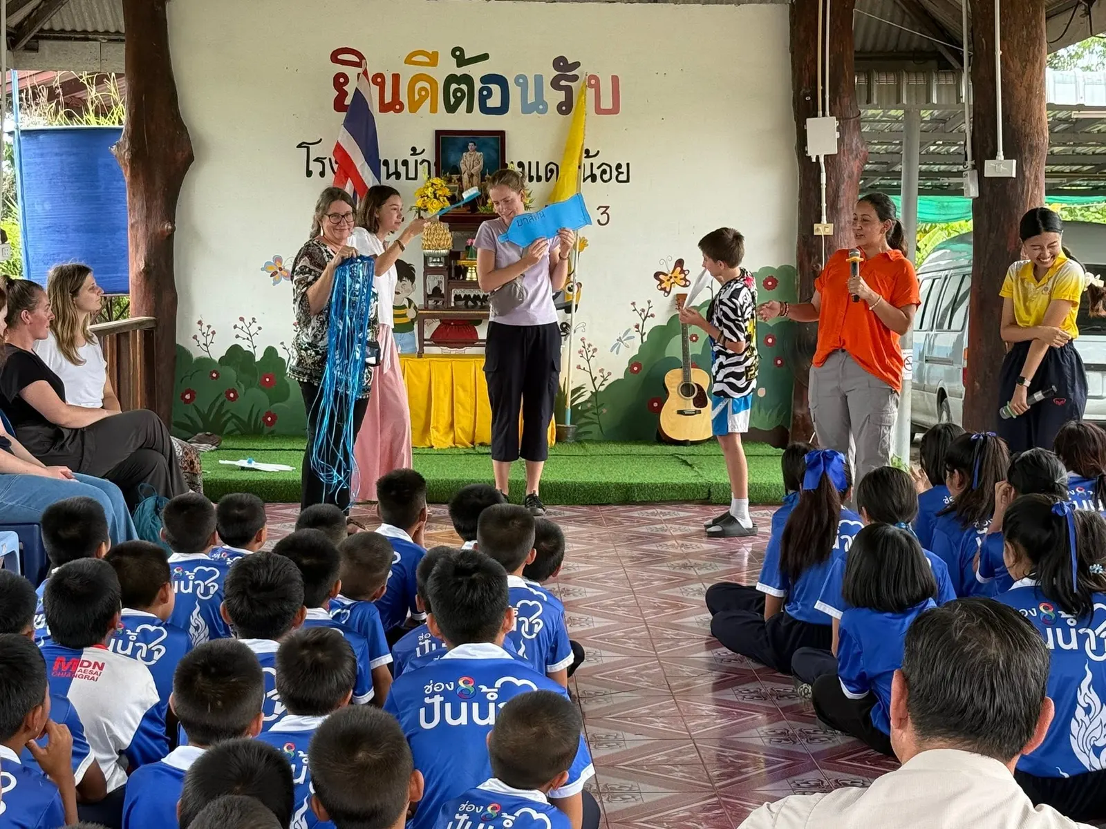 Volunteers sing and play guitar for students at a school welcome programme